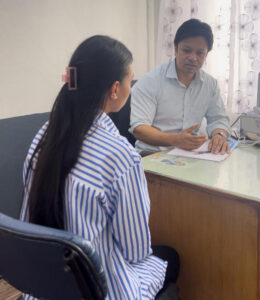 Dr. Rajan Babu Tajhya conducting a thorough dermatological consultation with a patient in his modern clinic, discussing personalized treatment options